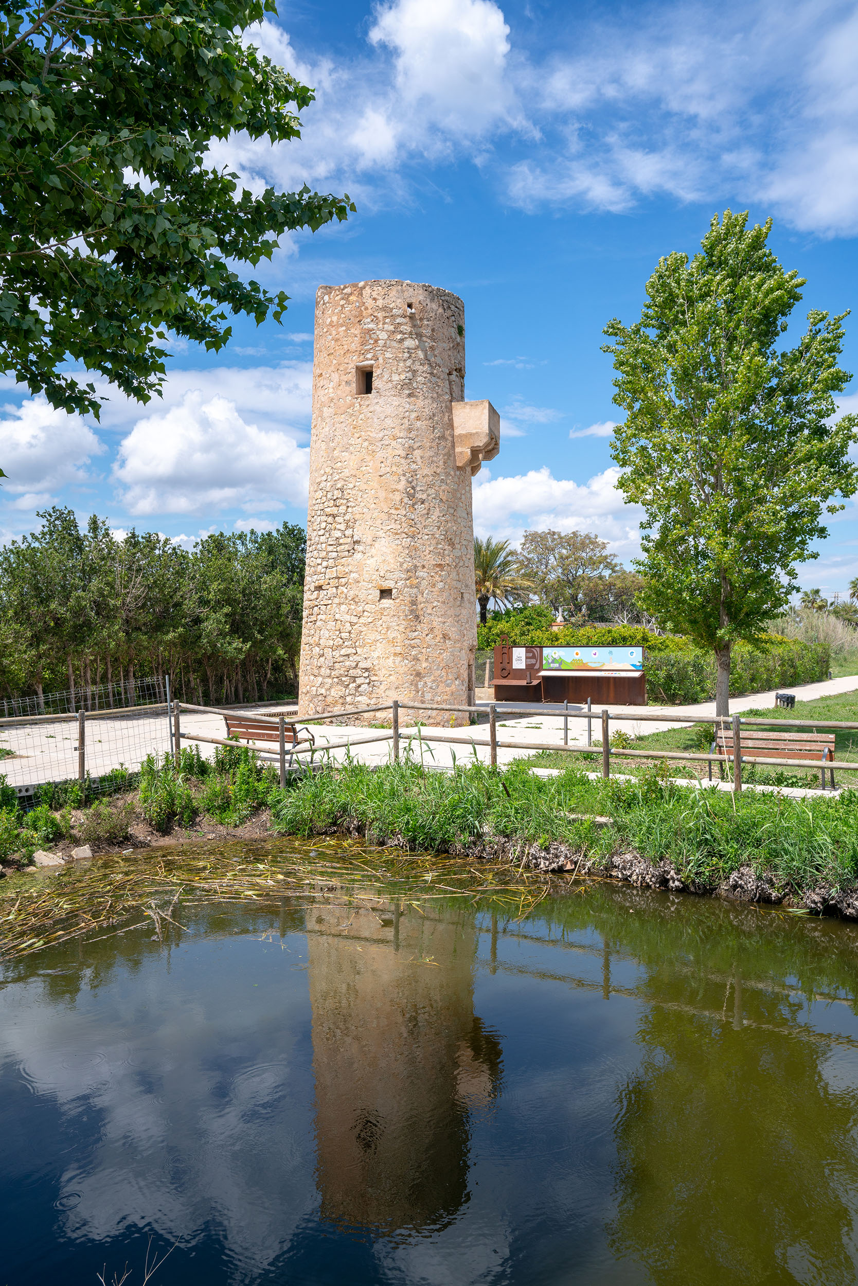 Torre de Guaita junto al entorno de agua y vegetación en Tavernes